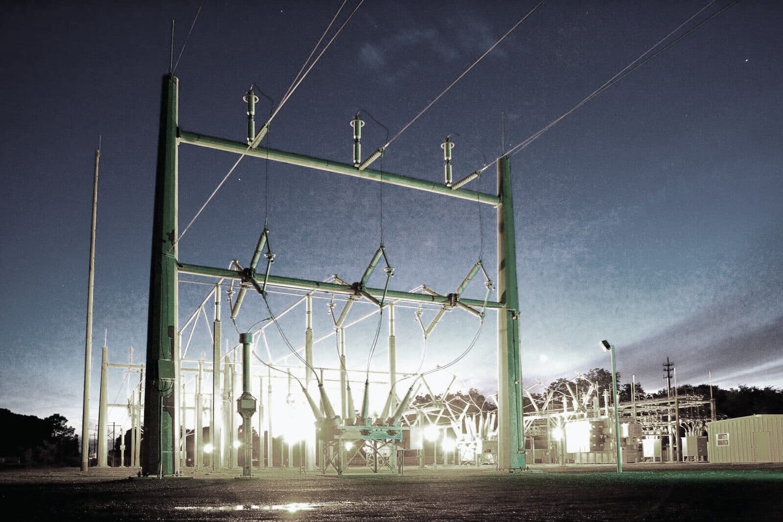 A high-voltage switchyard energised against a night sky