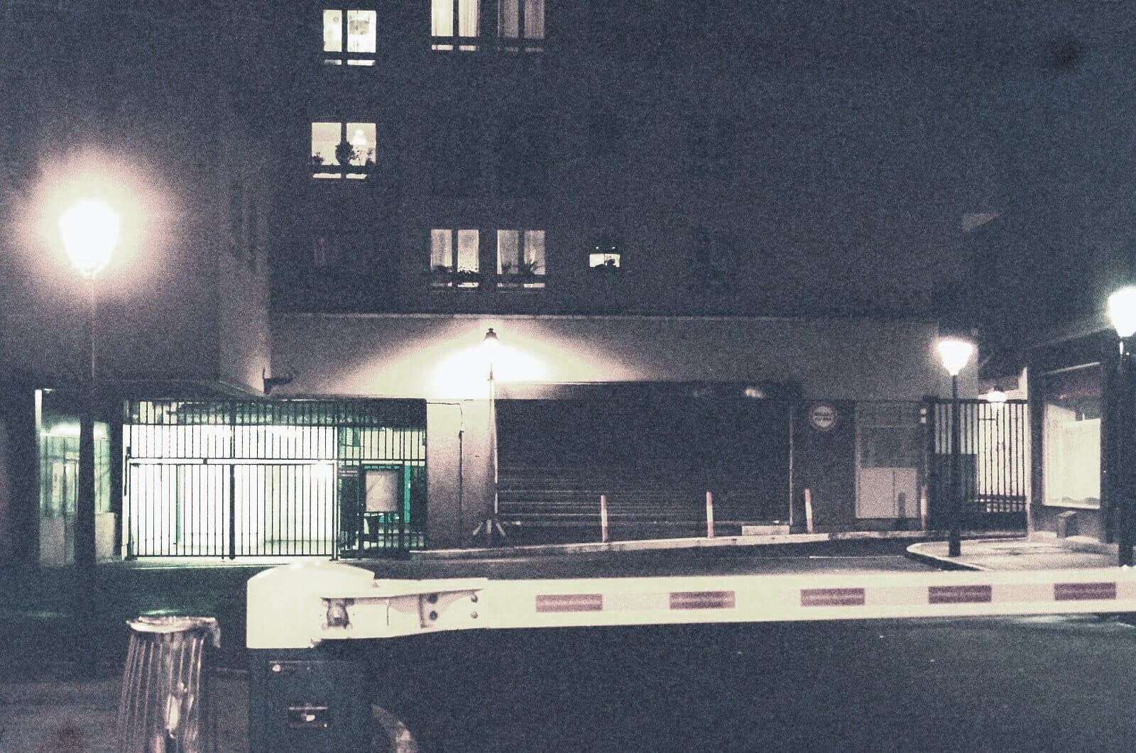 A guard cabin and boom barrier at a residential gate after dark