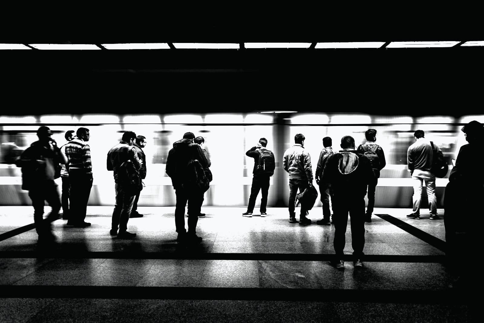 Silhouettes of people walking a corridor toward the light